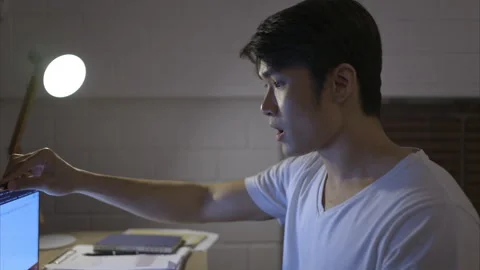When the laptop was turned on, a young Asian man working overtime Stock Footage 255033597