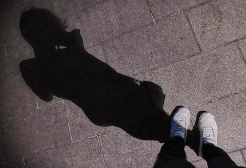 When looking down at the shadow of a woman on a concrete road, The sunlight t Stock Photos