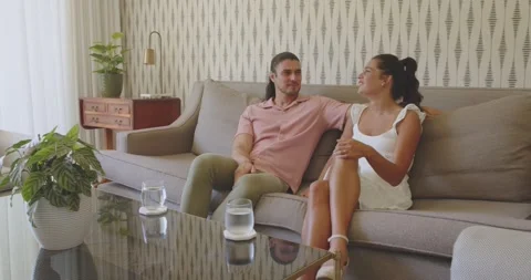 When man leaning forward and smiling, couple talking on sofa for friendly chat, Stock Footage 316611099