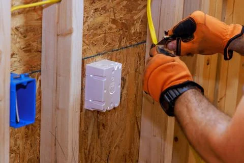 When a new building is being constructed, an electrician connects wires to Stock Photos