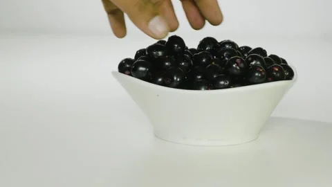 When a person takes Java plum fruits from the bowl, the fruits fall down 4k Video stock 252207005