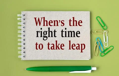 WHEN IS THE RIGHT TIME TO TAKE LEAP - words on a gray notebook with pen and p Stock Photos