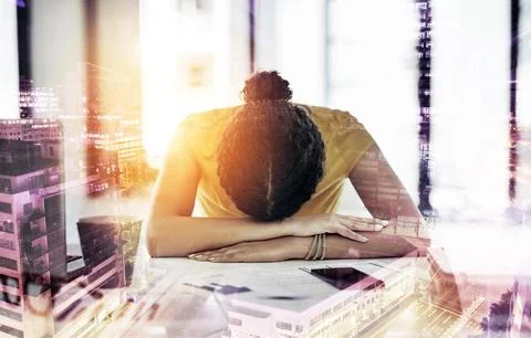 When will this day end. a young designer with her head down on her office desk. Stock Photos