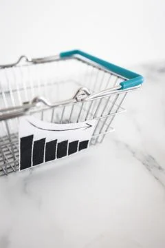 When will inflation go down. shopping basket with graph showing prices drop.. Stock Photos