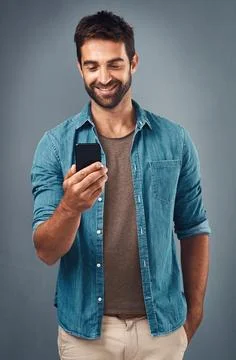 When you get a notification from your crush. Studio shot of a handsome young man Stock Photos