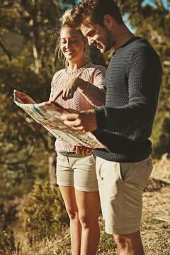 Where will we go next. a young couple looking at a map while out hiking. Fotos Stock