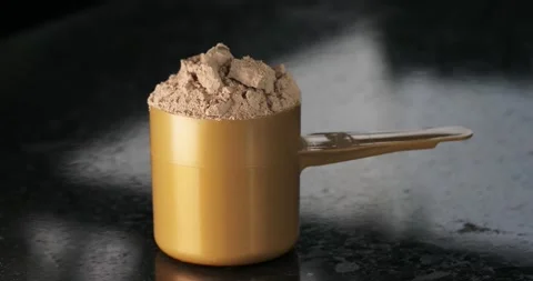 Whey protein in a measuring spoon close-up on a dark background with movement Stock Footage 153038854