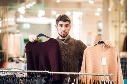 Which one to pick The concept of choice. A teenager with two sweaters next to Stock Photos
