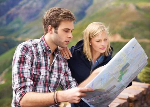 Which way should we go. A shot of a young couple looking at a map on their road Fotos Stock