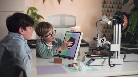 While 3D printer working, two boys discuss and research printed part Stock Footage 335379845