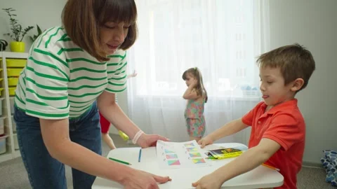 While all the children are having fun, the boy helps the teacher. Stock Footage 253987705