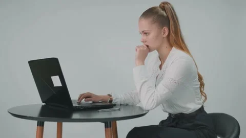 While busiess lady is typing a document at the computer she also is biting her Stock Footage 157936871