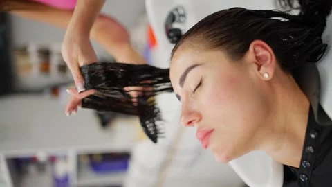 While the client is resting in the hairdressing sink, the master combs her hair. Stock Footage 325308347