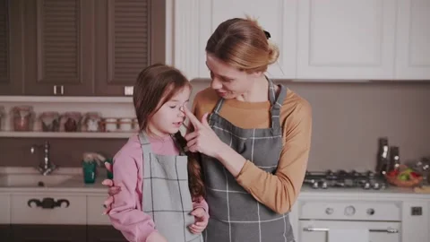 While making a cake, Mom laughingly smears her daughter's nose with cream. Stock Footage 234185896