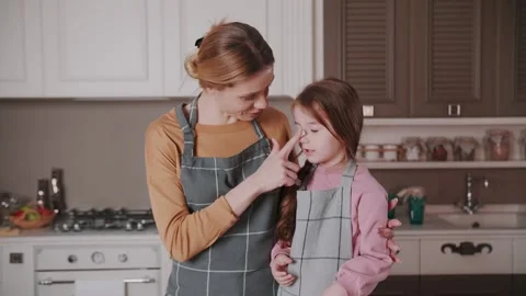 While making a cake, Mom smears her daughter's nose with cream, laugh. Stock Footage 234185839