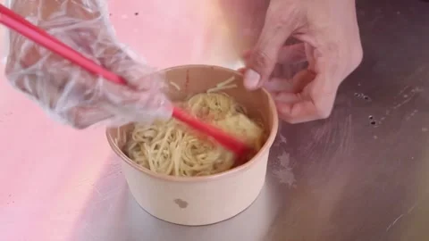 While mixing the noodles in a bowl using chopsticks and adding chicken Video stock 272298932