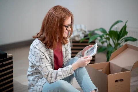 While moving to a new place of residence, the girl disassembles the boxes and Stock Photos