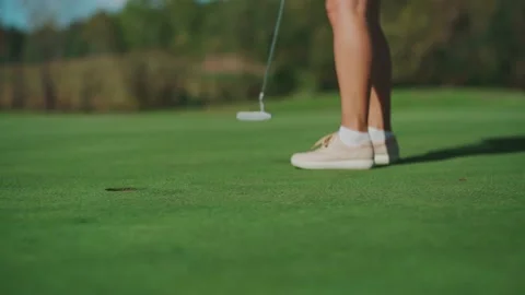 While playing golf, a girl hits the ball with a club and it hits the hole Video stock 213718532
