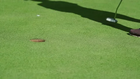 While playing golf, a girl hits the ball with a club and it hits the hole Stock Footage 217378262