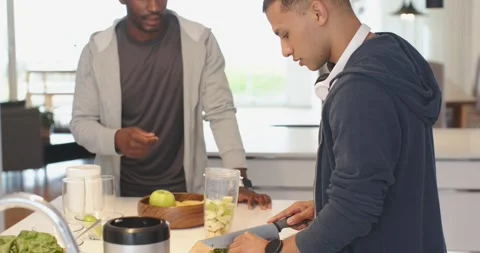While sharing feedback, diverse male friends chopping greens into blender jar at Stock Footage 341240863