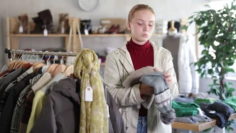 While shopping, girl browsing goods items and choose elect warm hat in store Stock Footage 328136133