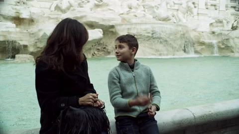 While sitting on the ledge of the Trevi Fountain, an Italian mother counts to th Stock Footage 199457924