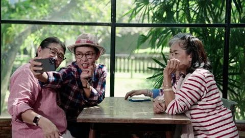 While sitting at table waiting for food ordered in cafe, senior women Stock Footage 295828284