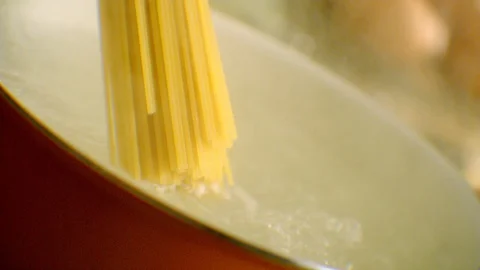 While spaghetti falls into the boiling water in slow motion. Stock Footage 128954576