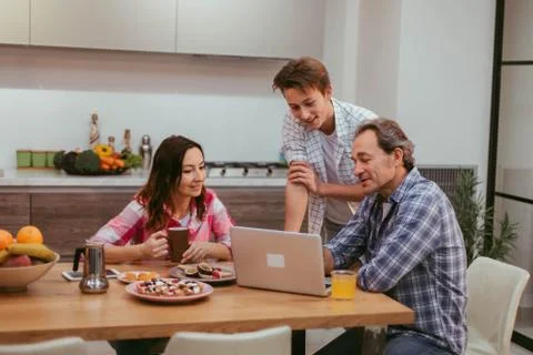 While taking the breakfast and drinking coffee mature couple and child in the Stock Photos