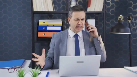 While talking about work problems on the phone in the office, he gets angry  Stock-Footage 233313667