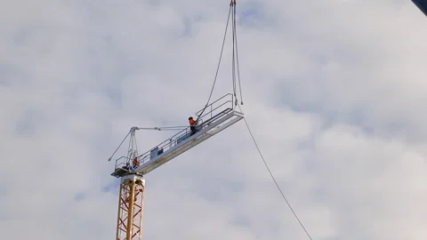 While two men work on dismantling a crane, one grabs cable from a second crane Stock Footage 196145297