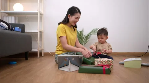 While in vacation at home, a mother gift wrap with little kid 스톡 동영상 310098465