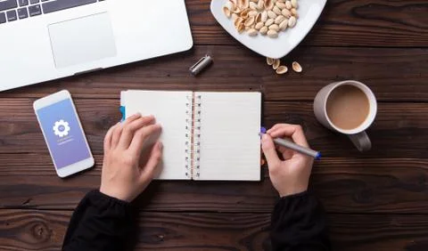 While waiting for installing update on smartphone a woman write something on Stock Photos