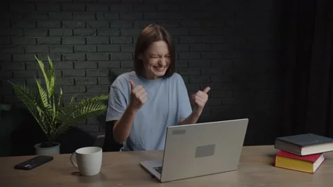While working on a laptop, a female freelancer experiences the joy of Stock Footage 233791439