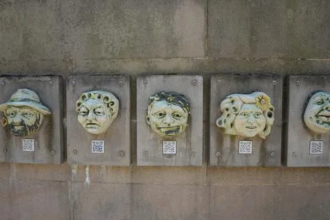 Whimsical Ceramic Faces With Qr Codes On A Concrete Wall, Derby, England Stock Photos