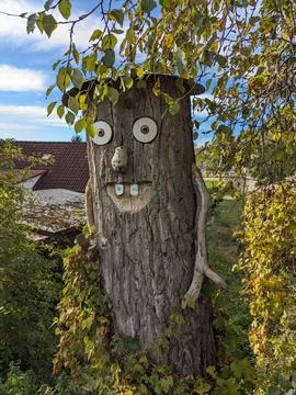 Whimsical face decoration attached to a tree trunk Stock Photos