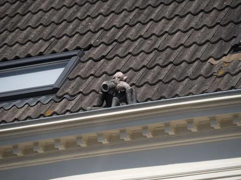 Whimsical Gutter Ghost Sculptures on a Tiled Roof Stock Photos