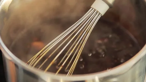 Whisk in a boiling pot. Heating crushed pecan nuts and melted chocolate. Stock Footage 236654740