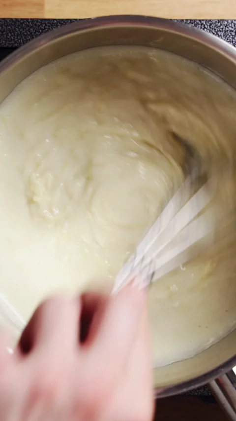 Whisk mixes grated cheese into smooth white sauce. Stock Footage 342105445