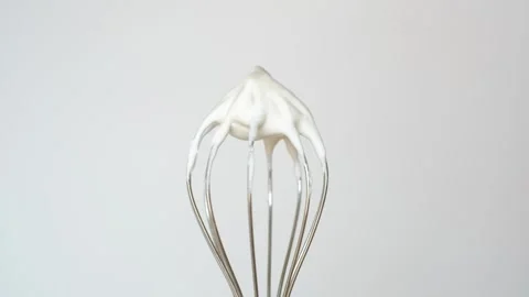Whisk with whipped cream on gray background close-up. Stock Footage 241964092