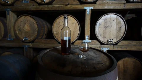 A whiskey bottle and sample glass sit on top of a wooden cask surrounded Stock Footage 119281118