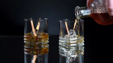 Whiskey, Brandy or cognac Pouring into Glass, on black background. Slow motion Stock Footage 153529901