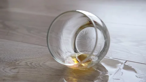 The whiskey has spilled, an empty glass is lying on the floor. Stock Footage 168124482