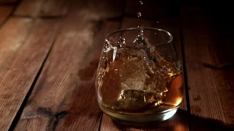 Whiskey on Ice Splashing in a Glass on a Rustic Wooden Table Vídeos de archivo 331102285