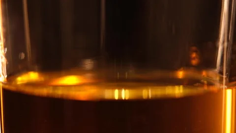 Whiskey macro close up of ice cube dropping into a glass of whisky or Stock Footage 128576517