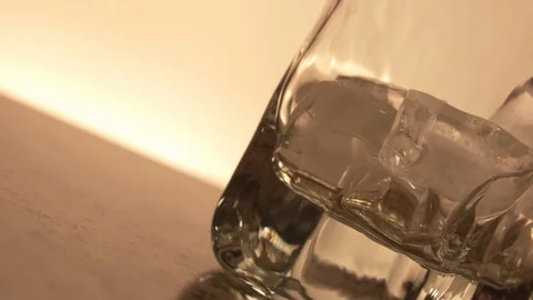 Whiskey is poured into a glass with ice slow motion. Close-up Stock Footage