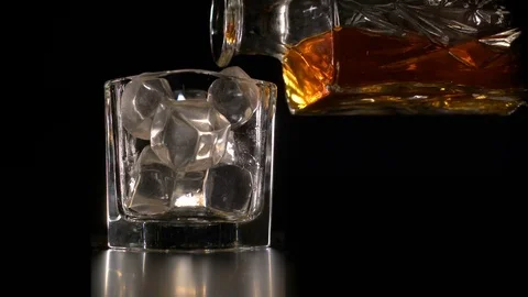 Whiskey on the rocks poured from a rystal decanter Stock Footage 70528285