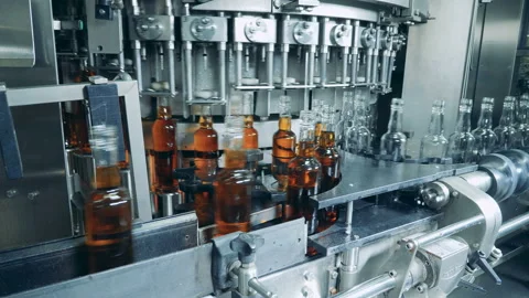Whiskey, scotch, bourbon production. Process of bottles filling with liquor at Stock Footage 103264404