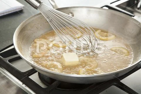 Whisking Butter Into Piccata Sauce in a Skillet Stock Photos