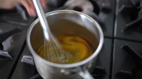 Whisking egg in a large pot over a stove Stock Footage 274497115